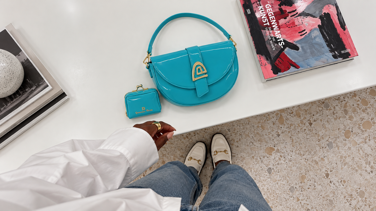 Sac turquoise présenté en nature morte sur une table blanche — Deveaux Paris